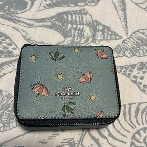 Coach travel jewelry case. It has a blue background with umbrellas on pattern.